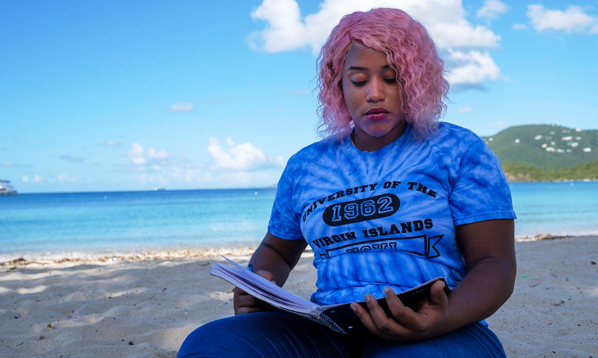 UVI student reading on Brewer's Bay Beach on OEK Campus