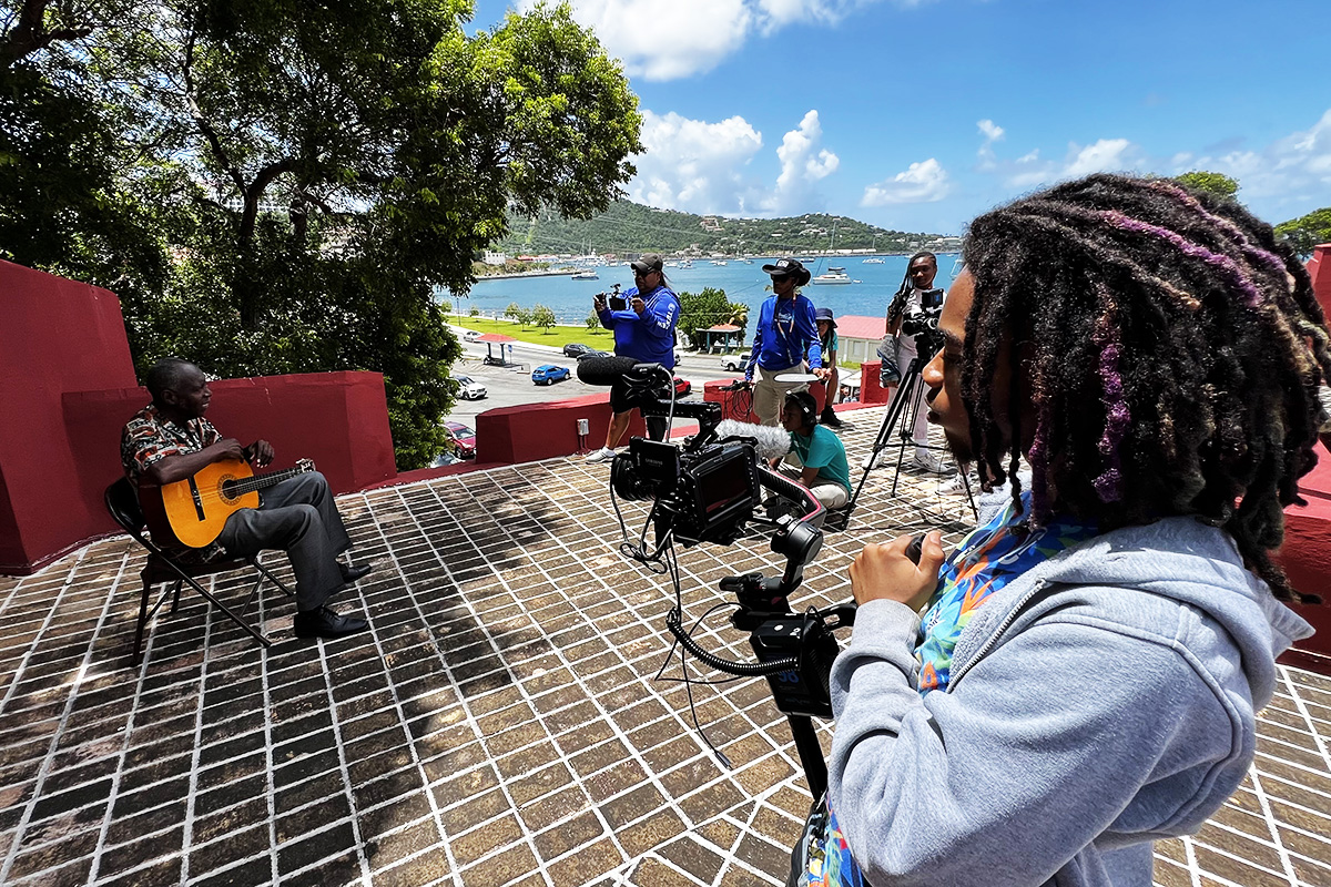 Youth Moviemaking Workshop students capture video of Cultural Bearer and Storyteller Glenn Kwabena Davis at Fort Christian. 